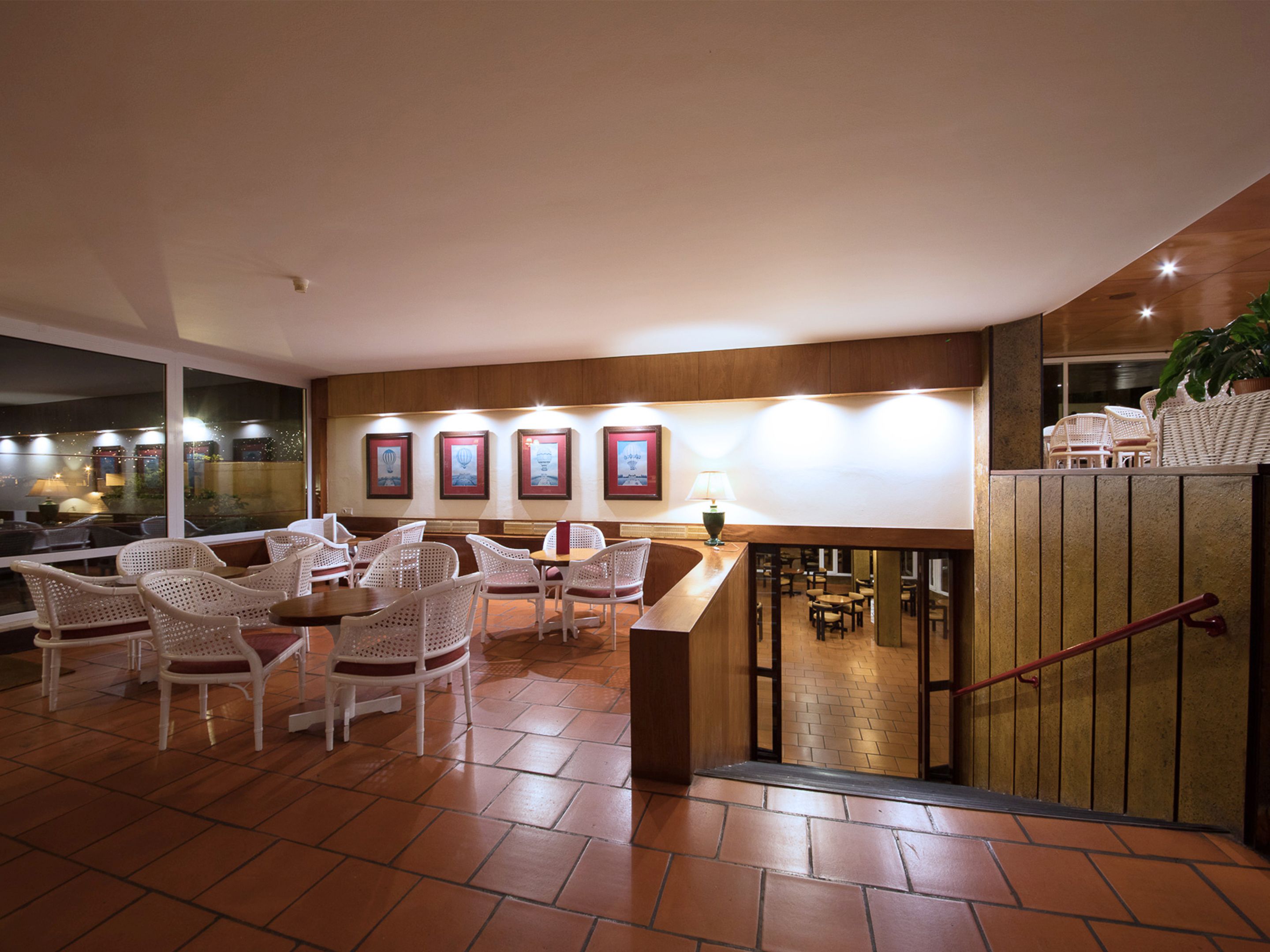 A hotel lobby with wicker chairs, a reception desk, and framed artwork on the wall.