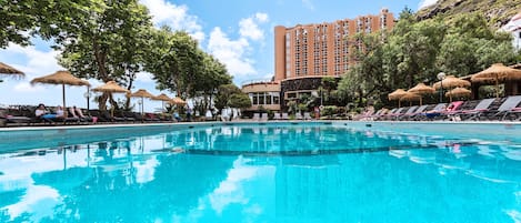 Una piscina al aire libre, sombrillas, tumbonas