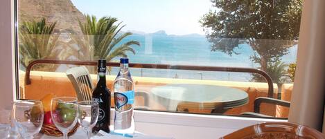 A table set for two with a view of the sea and hills.