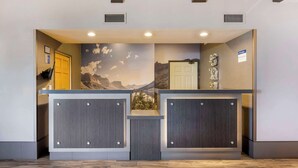 A reception desk with a mountain mural, two doors, and a small statue on the right.