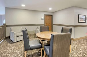 Un salón de conferencias con una mesa redonda, cuatro sillas, un sofá y una puerta.