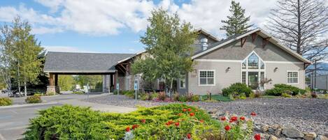 A two-story building with a covered entrance and a landscaped garden with colorful flowers.