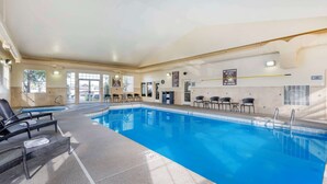 An indoor swimming pool with lounge chairs and a no diving sign.