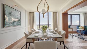 A dining area with a table set for six, a hanging light fixture, and a large abstract painting on the wall.