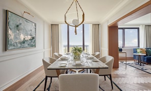 A dining area with a table set for six, a hanging light fixture, and a large abstract painting on the wall. - Jumeirah Carlton Tower London (London)