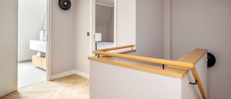 A modern room with a wooden bench, a mirror, and a door leading to another room.