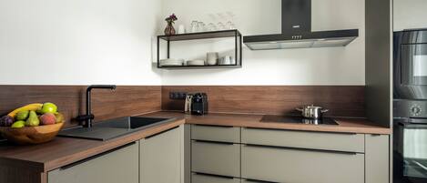 A modern kitchen with a wooden countertop, a built-in sink, and a stainless steel range hood.