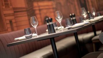 Ein Restaurant mit einem langen Tisch, gedeckt für ein Essen, inklusive Weingläsern, Tellern und Besteck.