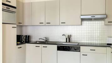 Una cocina moderna con armarios blancos, un lavamanos de acero inoxidable y un lavavajillas.