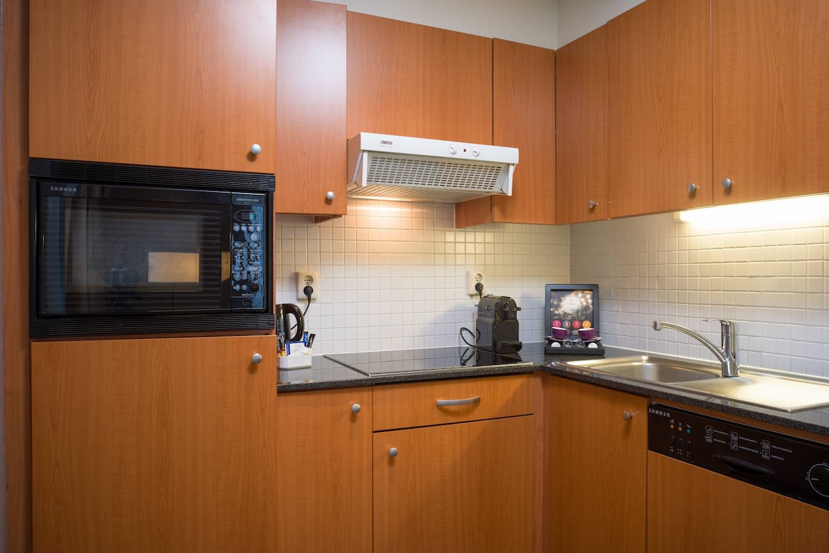A kitchen with wooden cabinets, a built-in microwave, a coffee machine, and a dishwasher.