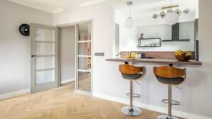 A modern kitchen with two bar stools, a wooden countertop, and a hanging light fixture. - Marriott Executive Apartments Brussels, European Quarter (Brussels)