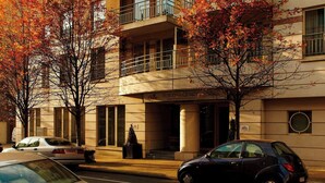 A multi-story hotel with balconies, a parking area, and autumn trees. - Marriott Executive Apartments Brussels, European Quarter (Brussels)