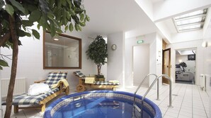 A spa area with a blue pool, lounge chairs, a wooden bench, and a large mirror. - Marriott Executive Apartments Millennium Court (Budapest)