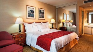 A hotel room with a large bed, two bedside lamps, a nightstand, a chair, a dresser, and a mirror. - Marriott Executive Apartments Millennium Court (Budapest)
