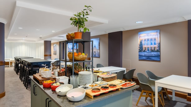 A hotel dining area with a buffet setup, including various food items and a potted plant on a shelf. - Marriott Executive Apartments Millennium Court (Budapest)