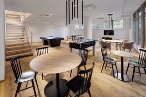 A modern indoor space with a pool table, foosball table, and a billiards table. There are multiple seating areas with chairs and tables. - Mamaison Residence Downtown (Prague)