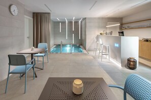 A modern hotel room with a pool, a bar area, and seating arrangements. - Mamaison Residence Downtown (Prague)