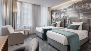A hotel room with two beds, a sofa, a chair, and a desk. - Mamaison Residence Downtown (Prague)