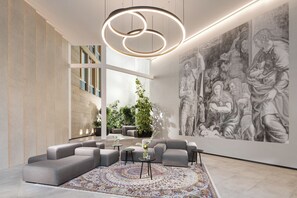 A modern interior with a large abstract painting, a circular light fixture, and a seating area with a patterned rug. - Mamaison Residence Downtown (Prague)