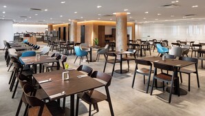 A spacious dining area with multiple tables and chairs, a kitchen in the background, and a modern interior design. - Mamaison Residence Downtown (Prague)
