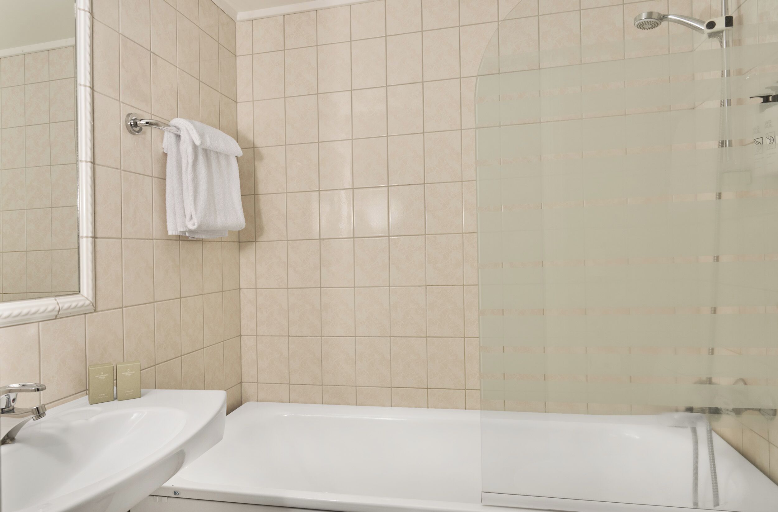 Een badkamer met een bad, een wastafel en een glazen douchecabine.