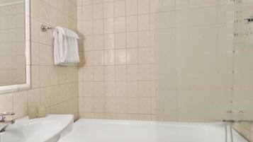 Un baño con bañera, lavamanos y cabina de ducha de vidrio.