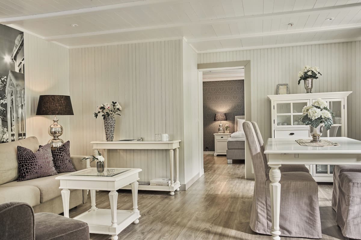 A room with a white sofa, a white coffee table, a white side table, and a white cabinet with glass doors.