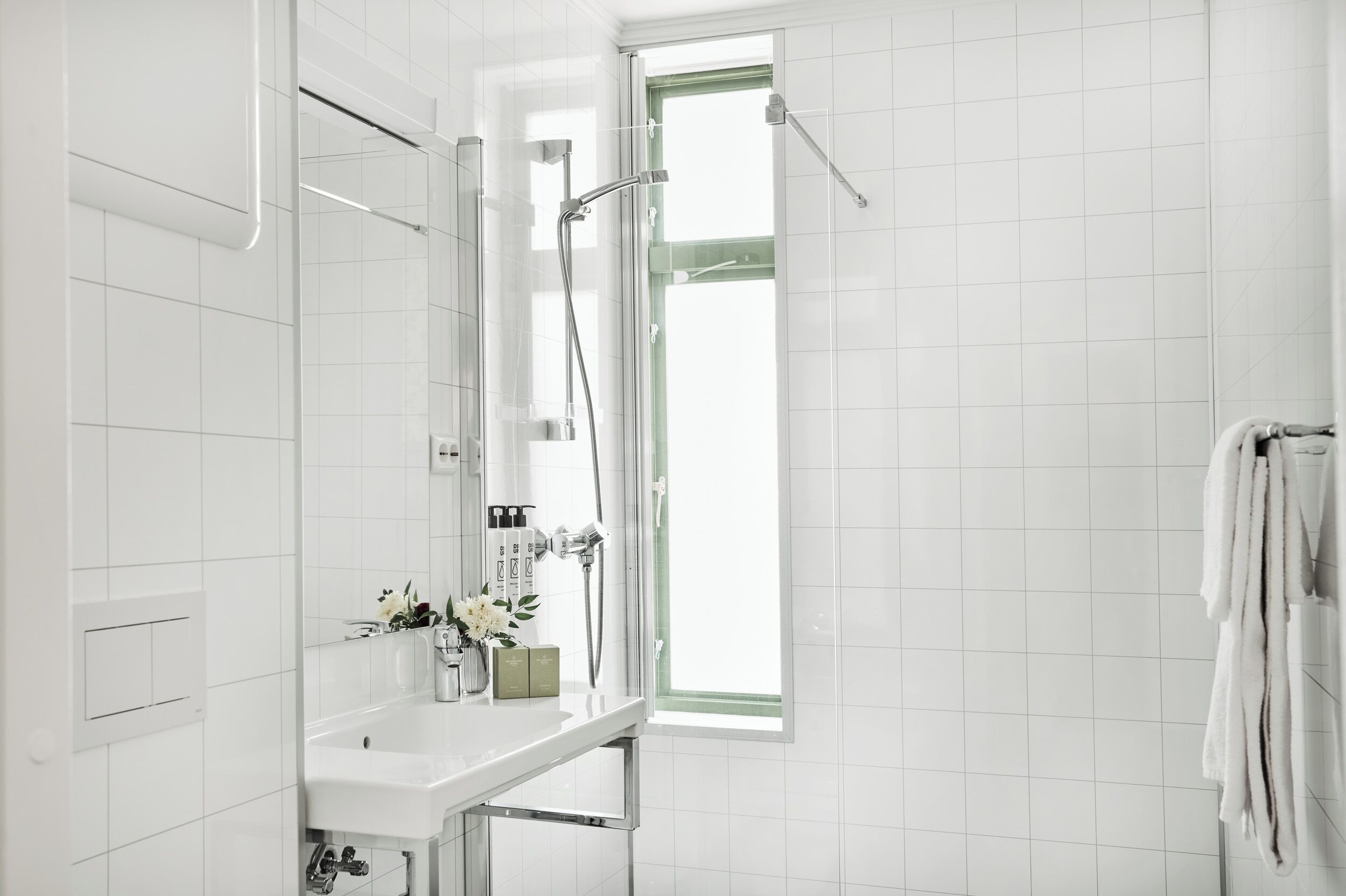 Un baño moderno con ducha, lavamanos y ventana.