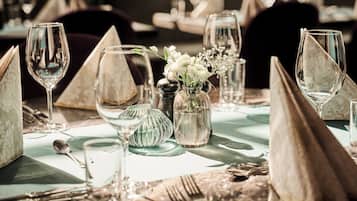 Une table dressée avec de la belle vaisselle, comprenant des verres à vin, une cuillère et un vase rempli de fleurs.