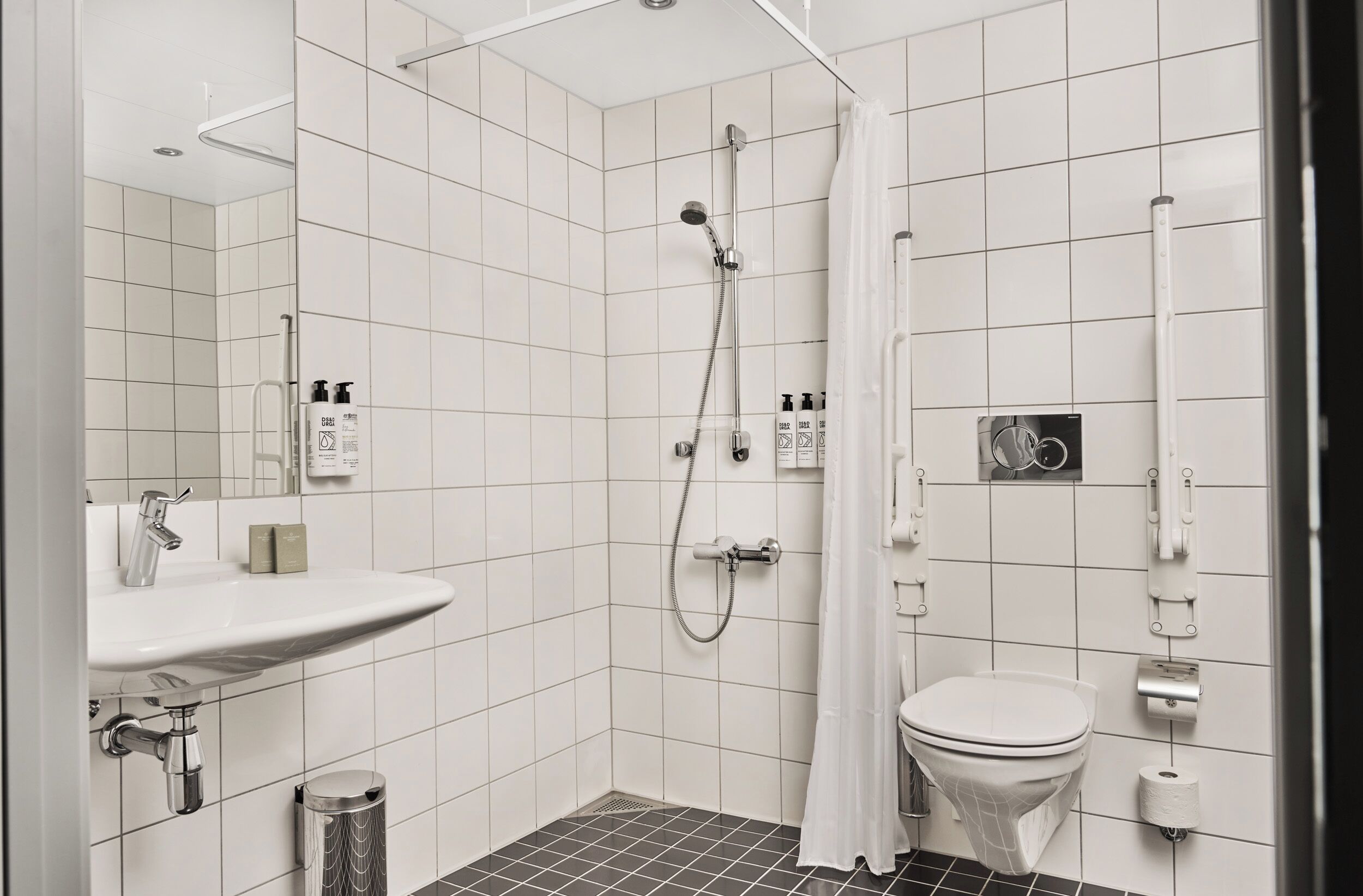 A modern bathroom with a shower, toilet, sink, and a mirror.