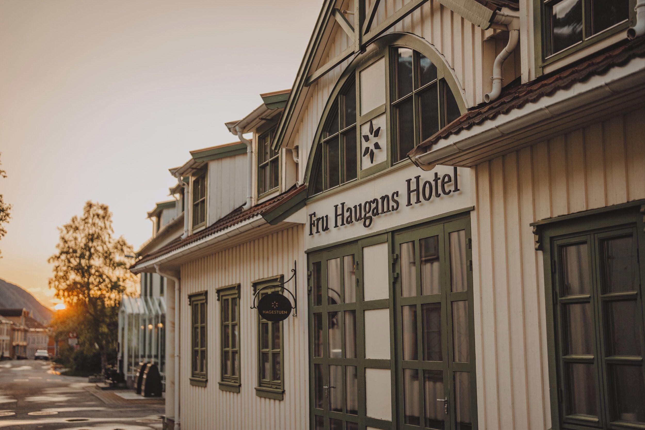 Exterior del Hotel Fru Haugens con un estilo arquitectónico clásico, que presenta grandes ventanales y un letrero destacado.