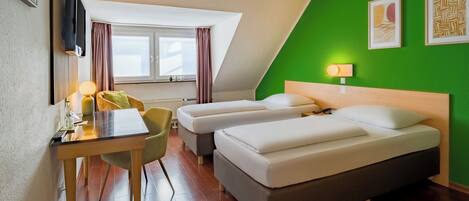 A hotel room with two beds, a desk with a chair, a TV, and a window with curtains.