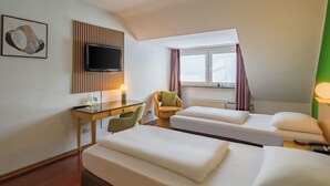 A hotel room with two beds, a desk, a television, and a window with curtains. - Rugs Hotel Düsseldorf – Self Check- In (Düsseldorf)