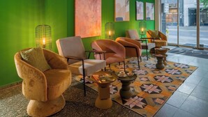 A modern lounge area with green walls, abstract art, and comfortable seating. - Rugs Hotel Düsseldorf – Self Check- In (Düsseldorf)
