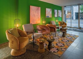 Un'area lounge moderna con pareti verdi, opere d'arte astratte e sedute confortevoli.