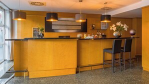 A reception area with a curved counter, two black bar stools, and pendant lighting. - Rugs Hotel Düsseldorf – Self Check- In (Düsseldorf)