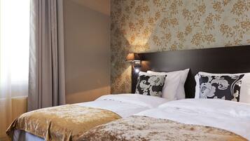 Een hotelkamer met een bed, nachtkastje, lamp en bloemenbehang.