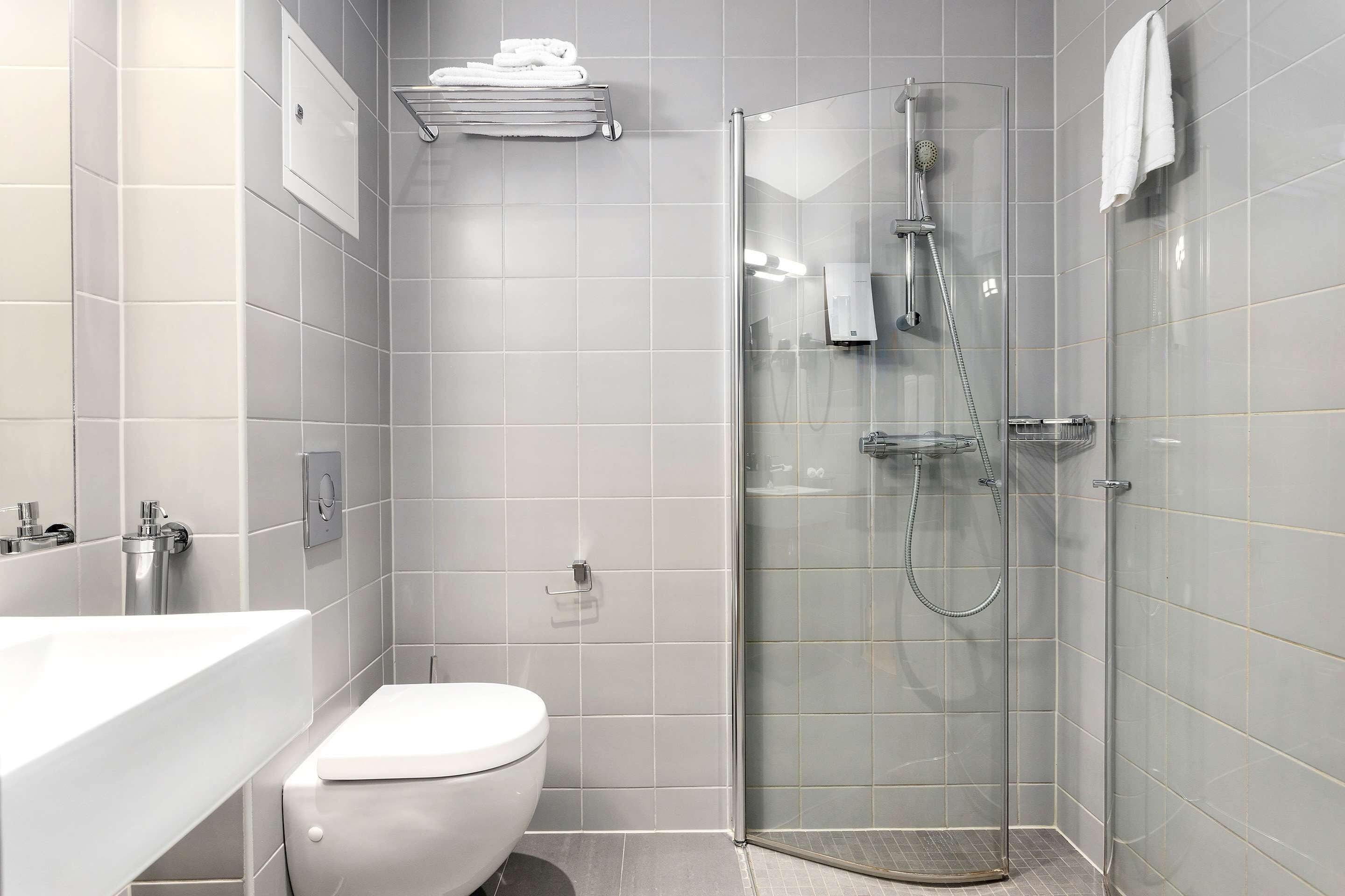 A modern bathroom with a glass-enclosed shower, a white toilet, and a sink.