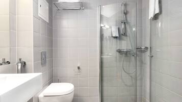 A modern bathroom with a glass-enclosed shower, a white toilet, and a sink.
