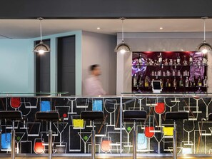 Zona de bar con diseño moderno, que incluye una barra de vidrio e iluminación colgante.