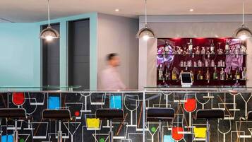 A bar area with a modern design, including a glass counter and pendant lighting.