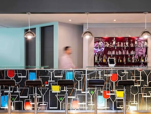 Un área de bar con diseño moderno, que incluye una barra de vidrio e iluminación colgante.