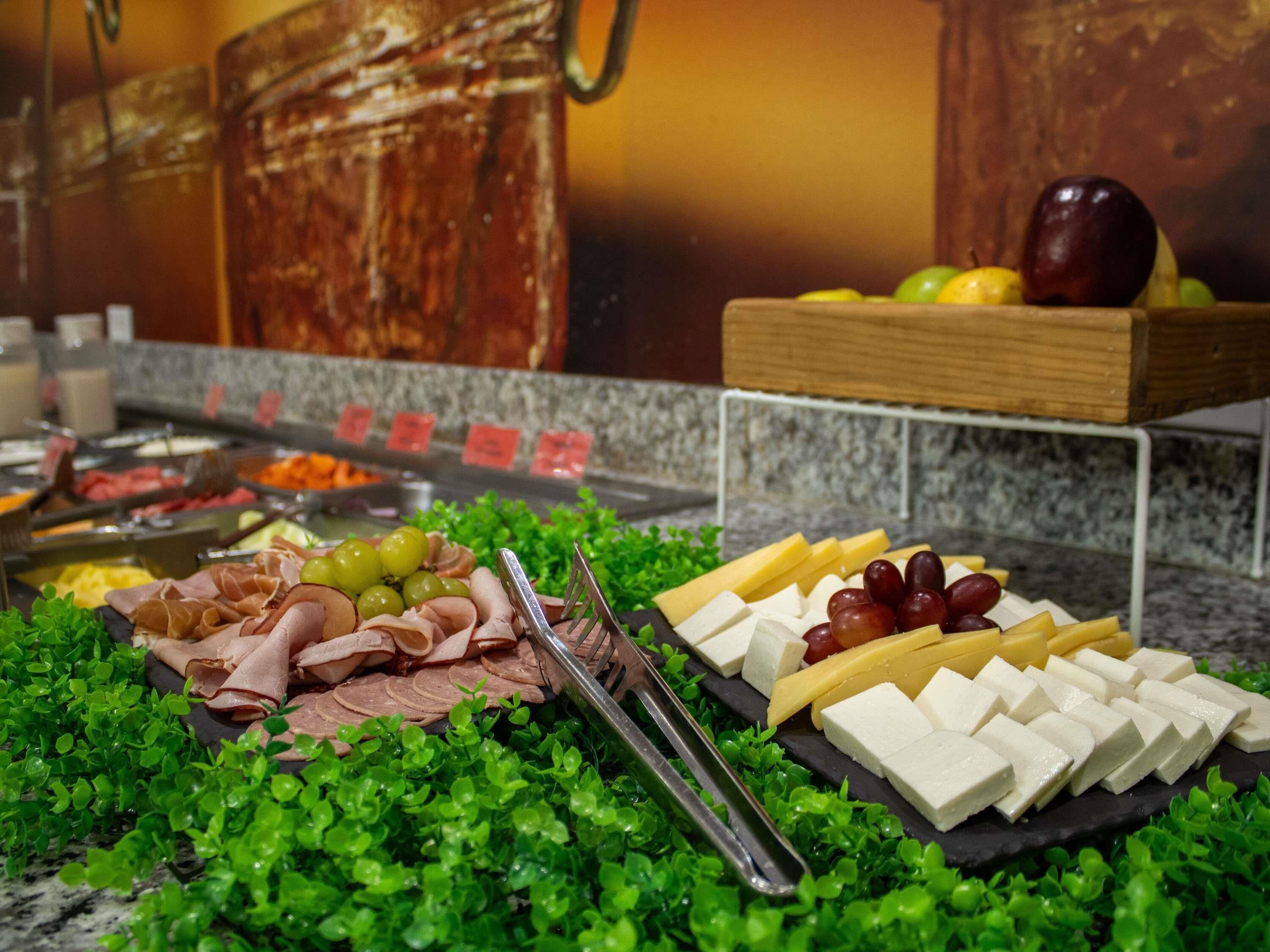 A buffet with various food options including meats, cheeses, and fruits.