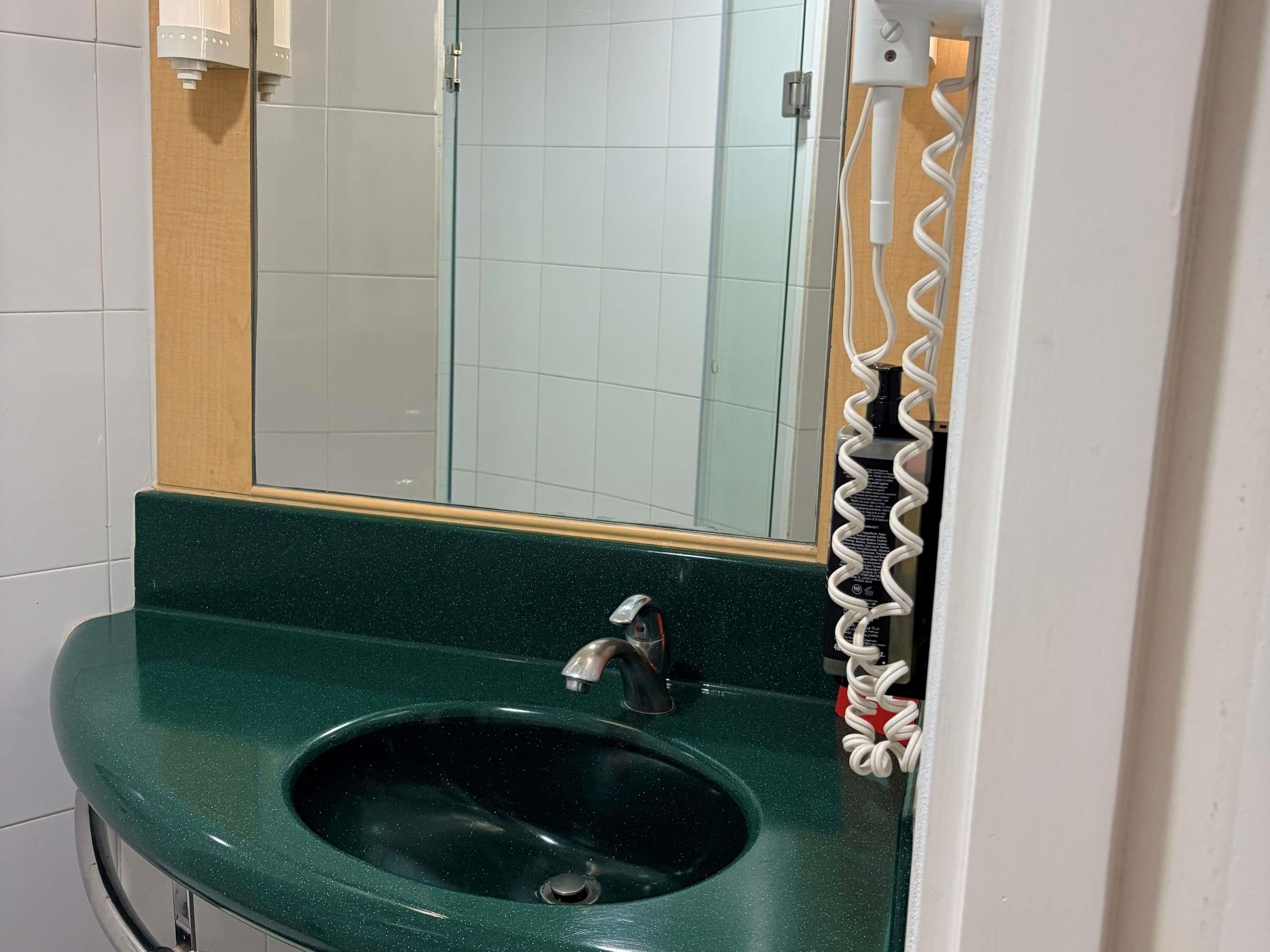 A bathroom with a green sink, a mirror, and a towel rack.