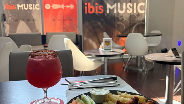 Interior de restaurante con una mesa dispuesta para comer, que incluye una bebida, un plato de comida y una servilleta.