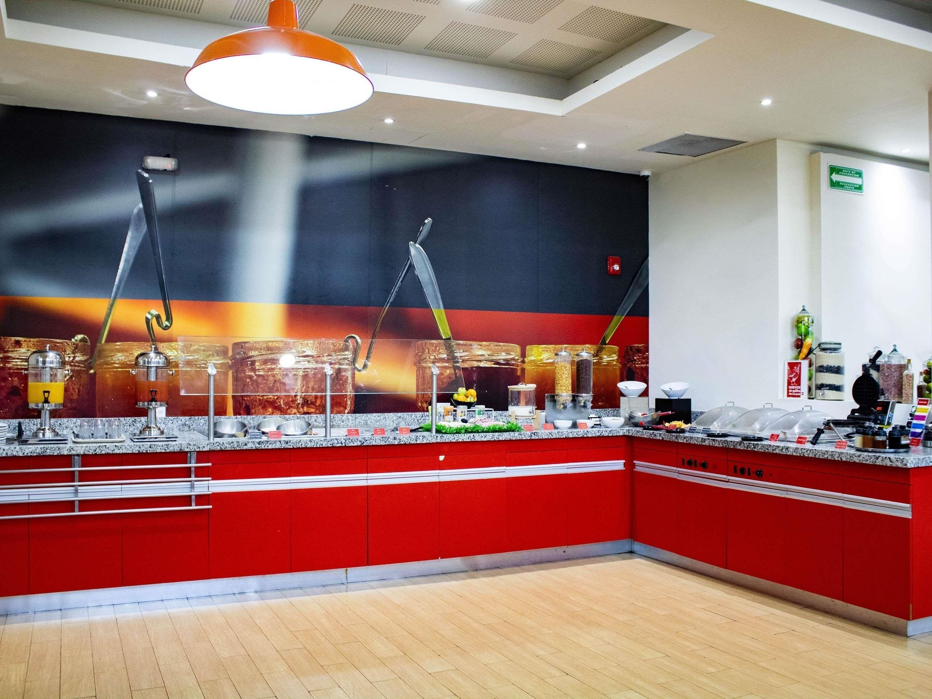 A modern kitchen area with a red and white color scheme, equipped with various appliances and utensils.