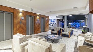 A modern lobby with a reception desk, seating area, elevators, and a staircase leading to upper floors. - SLAVIERO Moema (São Paulo)