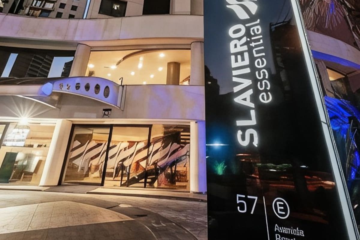 A hotel entrance with a modern design, a prominent sign for 'SLAVIERO Essential 57', and a view of surrounding high-rise buildings.