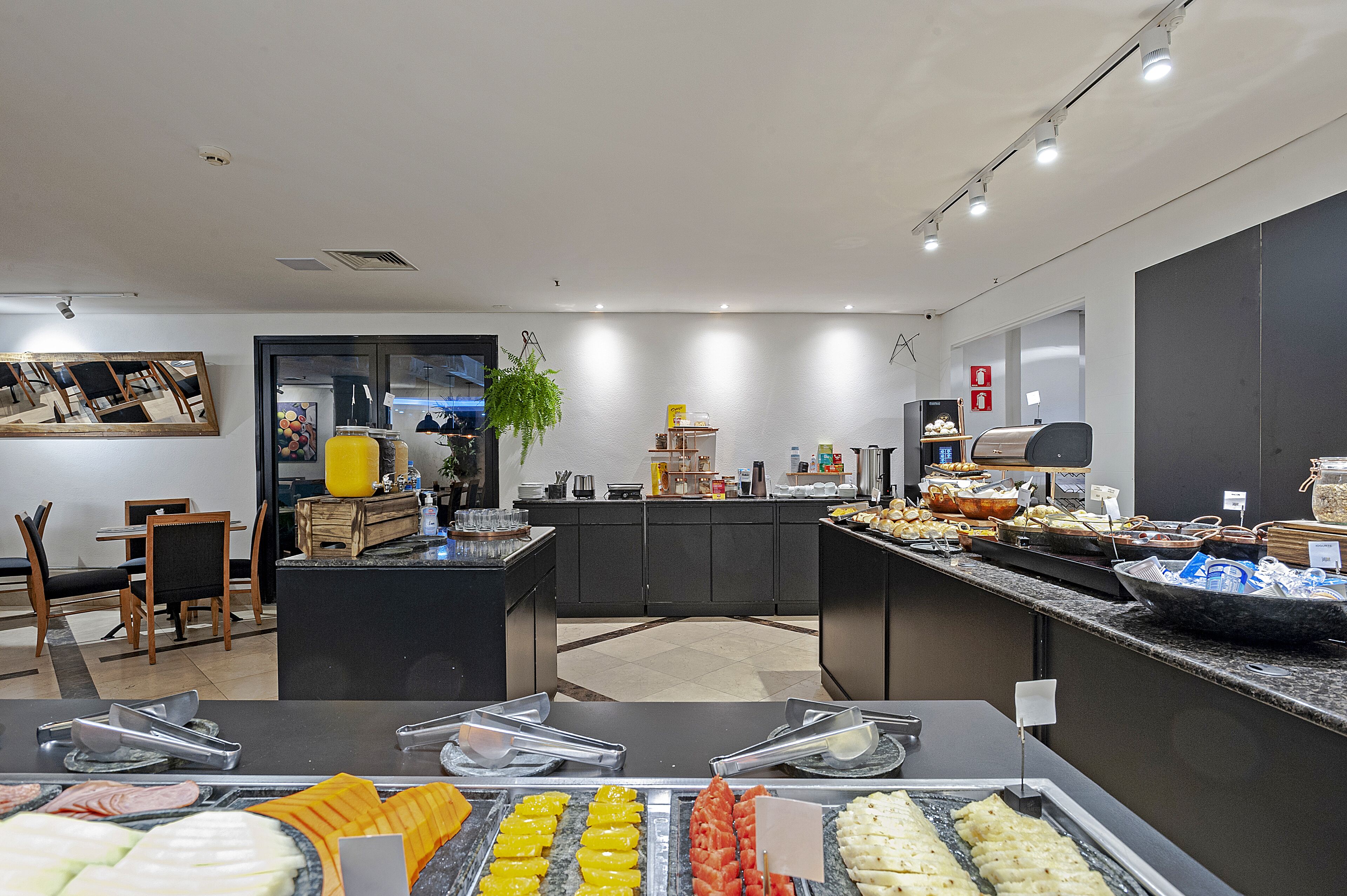 A modern kitchen with a buffet setup, including various food items and a seating area with chairs and a table.