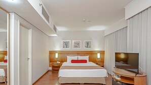 A hotel room with a large bed, a TV, a desk, and artwork on the wall. - SLAVIERO Moema (São Paulo)